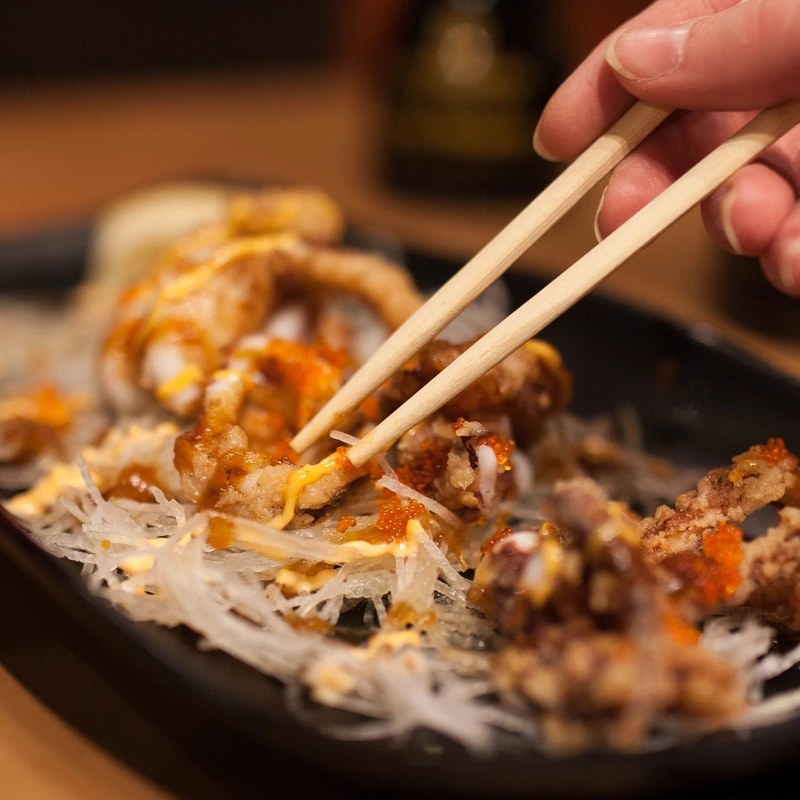 Chopsticks lifting golden fried food at Kinjo